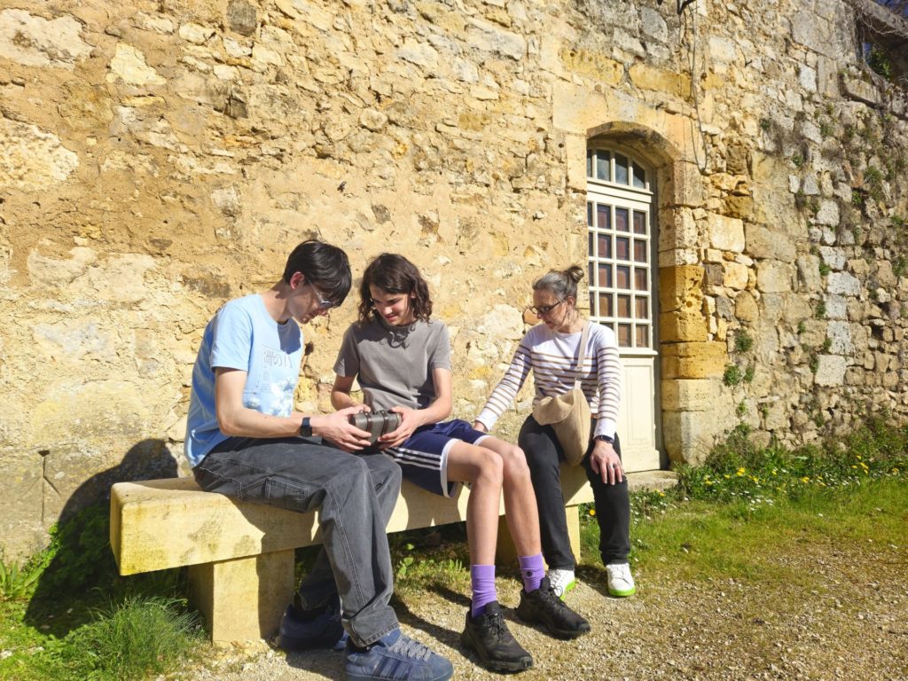 Trois participants de la Murder Party de Saint Jean de Côle assis devant le Château de La Marthonie.