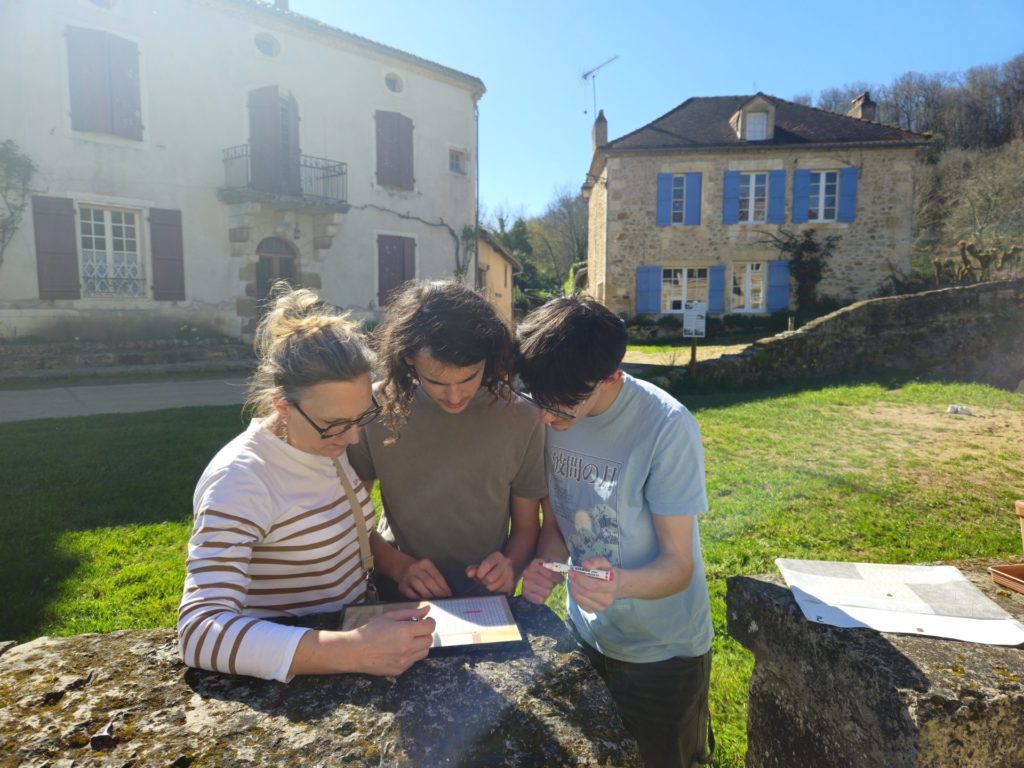 Trois participants de la Murder Party de Saint Jean de Côle résolvant une énigme devant la maison de l'octroi.